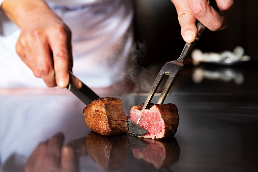 鉄板の上で焼いた牛肉を切り分ける様子